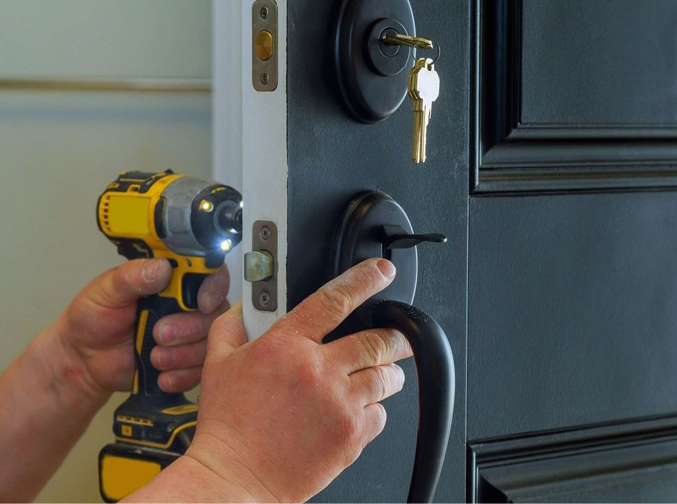 A person using a drill to install the door knob.