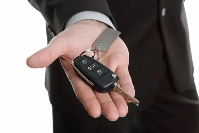 A man holding two keys to his car.